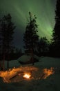 Fireplace in the forest with aurora borealis above. Royalty Free Stock Photo