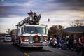 A firetruck driving through a Christmas parade with Santa on top of the firetruck