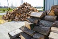 A firewood stacked in a pile, lying on the property near the metal garage, wooden background.