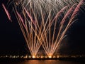 Fireworks burst in the night sky with light trails and clear base of fireworks over the sea Royalty Free Stock Photo