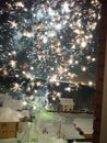 Fireworks bursts through the open window on a winter night.