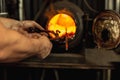 Close-up working powerful hands of male blacksmith making red hot metal in furnace, horn. Work process of heating metal