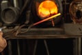 Close-up working powerful hands of male blacksmith making red hot metal in furnace, horn. Work process of heating metal