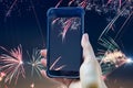Fireworks composing of a female hand holding a smartphone taking a picture