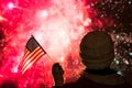 Fireworks at night. Woman in winter clothes with American flag.