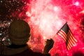 Fireworks at night. Woman in winter clothes with American flag.