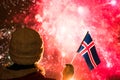 Fireworks at night. Woman in winter clothes with flag of Iceland on the New Year.