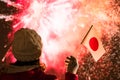 Fireworks at night. Woman in winter clothes with Japanese flag on the New Year.