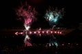 Fireworks in red and blue reflected in the water and many people in the dark night are watching, holiday and festival concept,