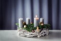 First advent with a burning candle on a wreath of white painted wood, fir branches and Christmas decoration against a purple-grey Royalty Free Stock Photo