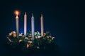 First advent candles burning on black background