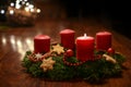 First Advent - decorated Advent wreath from fir branches with red burning candles on a wooden table in the time before Christmas,