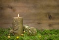 First advent: golden candle burning before wooden background.