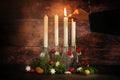 First advent, hand lighting one of four candles placed in bottles with fir branches and christmas decoration against a rustic dark Royalty Free Stock Photo