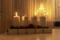 First advent light, four white candles on table with electic advent candlestick on background, the christmas period Royalty Free Stock Photo
