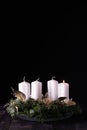 First Advent - Advent wreath from fir and evergreen branches with white burning candles on dark wooden table. Royalty Free Stock Photo