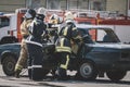 first aid after an accident on the road. Fireman with protective overalls and work gloves while breaking a car windshield