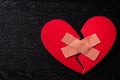 First Aid Band Cushioned Plaster Strip Medical Patch glued on red heart paper on wooden background. Heart broken, Love and Royalty Free Stock Photo