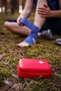 First aid kit and defocused injured tourist woman with sprain ankle in forest Royalty Free Stock Photo