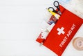 First aid kit in red bag on wooden table. Kit with patch, pills, scissors, masks, thermometer, elastic bandages. Top view, Royalty Free Stock Photo