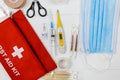 First aid kit in red bag on wooden table. Kit with patch, pills, scissors, masks, thermometer, elastic bandages. Top view, Royalty Free Stock Photo