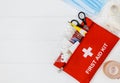 First aid kit in red bag on wooden table. Kit with patch, pills, scissors, masks, thermometer, elastic bandages. Top view, Royalty Free Stock Photo