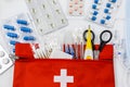 First aid kit in red bag on wooden table. Kit with patch, pills, scissors, masks, thermometer, elastic bandages. Top view, Royalty Free Stock Photo