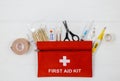 First aid kit in red bag on wooden table. Kit with patch, pills, scissors, masks, thermometer, elastic bandages. Top view, Royalty Free Stock Photo