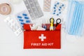 First aid kit in red bag on wooden table. Kit with patch, pills, scissors, masks, thermometer, elastic bandages. Top view, Royalty Free Stock Photo