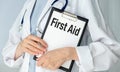 First AID text message on paper card in hands Doctor with stethoscope on white background. Royalty Free Stock Photo