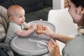 Mother feeding with vegetables or fruits pure baby on highchair Royalty Free Stock Photo