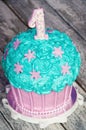 First birthday cake with a unit on a purple background with balls and paper garland. Royalty Free Stock Photo