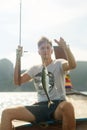 The first catch of many. a handsome young man fishing while out at sea on his boat.