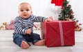 First Christmas: baby unwrapping a red present with a red checkered ribbon - cute little boy Royalty Free Stock Photo