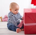 First Christmas: baby unwrapping a red present with a red checkered ribbon - cute little boy Royalty Free Stock Photo