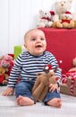 First Christmas: barefoot baby with moose amongst presents and c