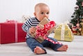 First Christmas: barefoot baby unwrapping a red present - cute l