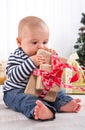 First Christmas: barefoot baby unwrapping a red present - cute l