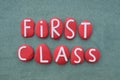 First Class, creative text composed with red colored stone letters over green sand