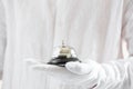 First-class service. Hand in white gloves holding hotel bell Royalty Free Stock Photo