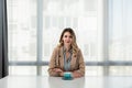 But first coffee. Young tired business woman in formal wear sitting in the office at empty desk with cup of coffee. Female white Royalty Free Stock Photo