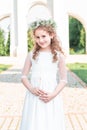 First communion girl. Portrait of cute little girl on white dress and wreath on first holy communion background church gate Royalty Free Stock Photo