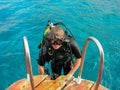 First dive in Red Sea near Aqaba resort in Jordan. Young scuba diver in equipment rises from emerald water