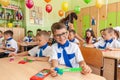 First-form schoolchildren in classroom at school desks on holiday of beginning of elementary school education. Happy boys at first