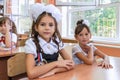 First-form schoolchildren in classroom at school desks on holiday of beginning of elementary school education. Happy girls at