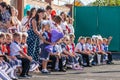 First-form schoolchildren and teacher at school on holiday of beginning of elementary education. Happy girls and boys at school