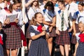 First-form schoolgirl at school on holiday of beginning of elementary education reading poetry. Girl with microphone declaiming Royalty Free Stock Photo