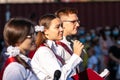 First-form schoolgirl at school on holiday of beginning of elementary education reading poetry. Girl with microphone declaiming