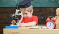 First former interested in studying, learning, education. Kid boy in academic cap work with microscope in classroom Royalty Free Stock Photo