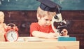 First former interested in studying, learning, education. Kid boy in academic cap work with microscope in classroom Royalty Free Stock Photo